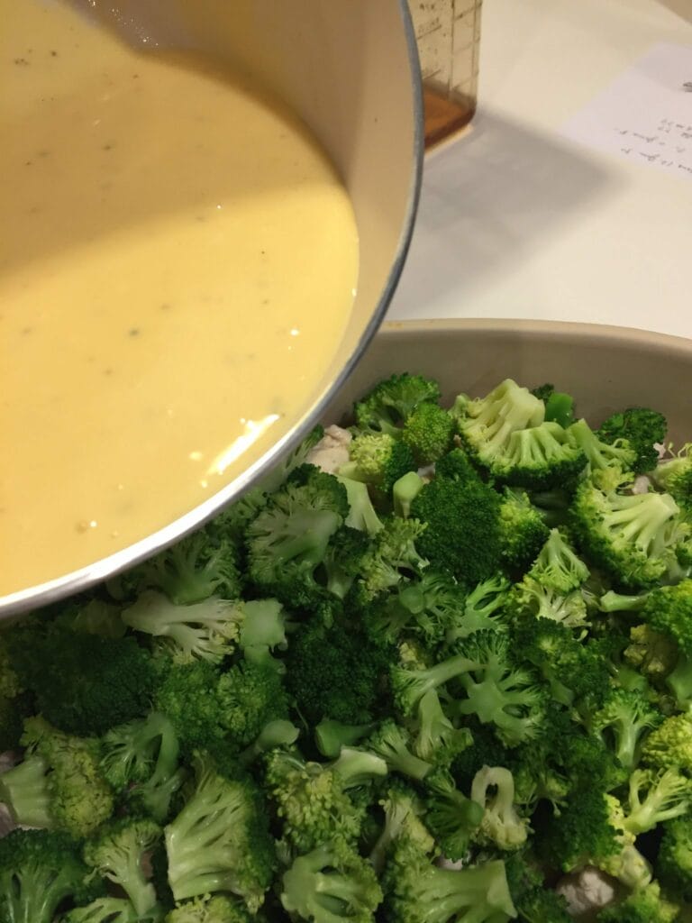 Chicken Divan from Scratch pouring the cheese sauce