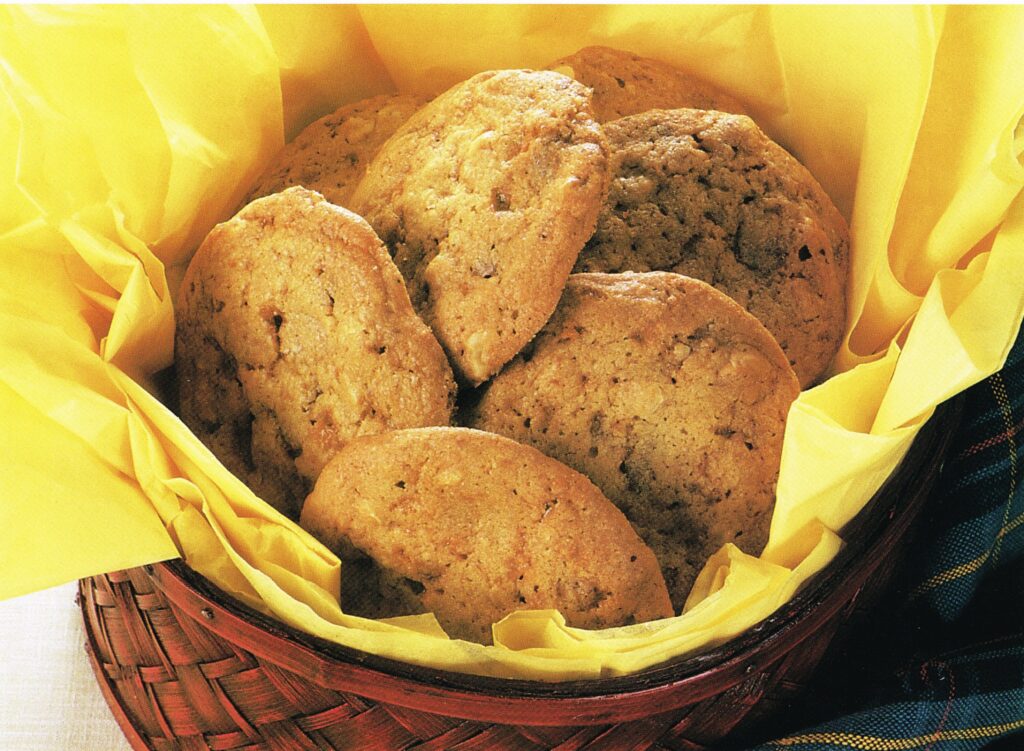 Crispy Butterscotch Cookies nestled in a basket with yellow paper.