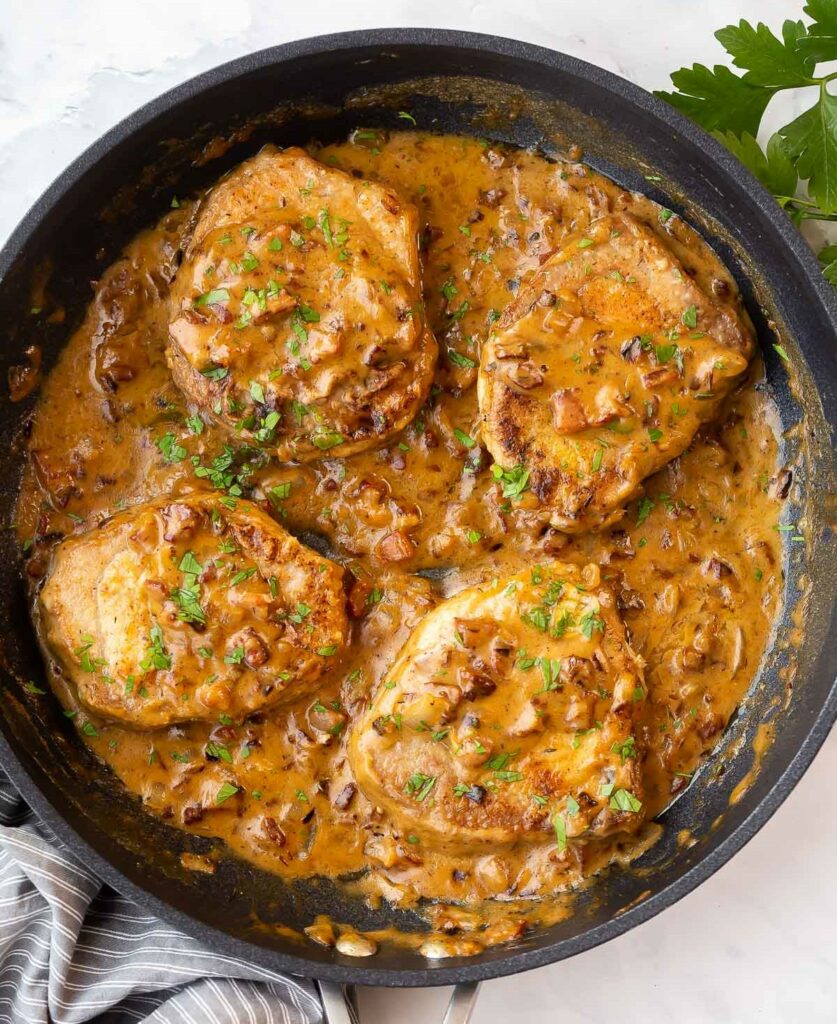 Smothered baked pork chops in cast iron skillet