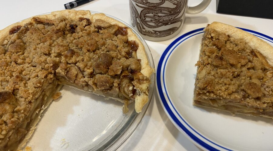 Homemade Apple Crumb Pie, sliced on a plate with coffee