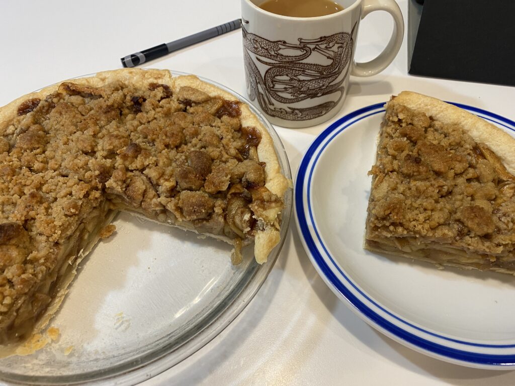 Homemade Apple Crumb Pie, sliced on a plate with coffee