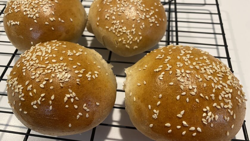 Four Homemade Sesame Seed Buns on a cooling rack
