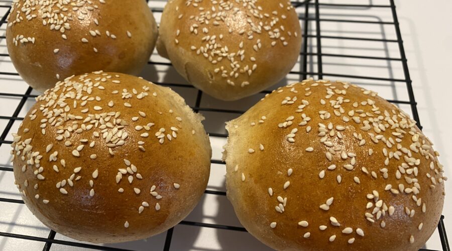 Four Homemade Sesame Seed Buns on a cooling rack