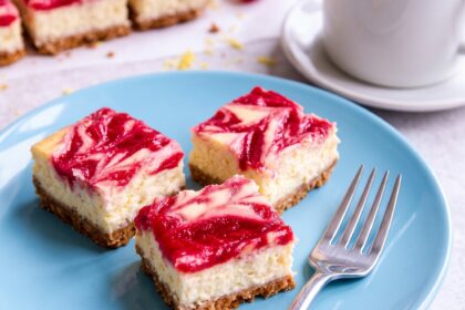 Lemon Raspberry Cheesecake Bars sitting on a plate with a fork.