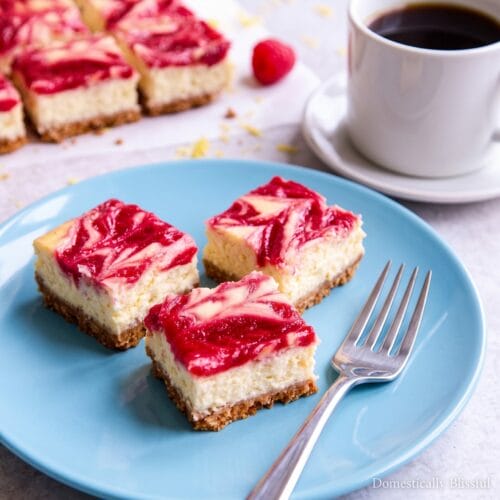 Lemon Raspberry Cheesecake Bars sitting on a plate with a fork.